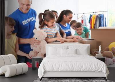 Volunteers with children sorting donation goods indoors Wall mural