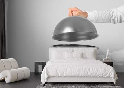 Waiter holding metal tray with lid on light background Wall mural