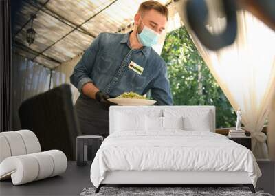 Waiter serving food in restaurant. Catering during coronavirus quarantine Wall mural