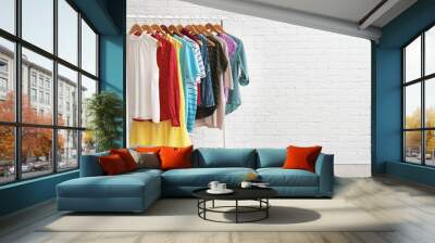 Wardrobe rack with stylish clothes and shoes near brick wall indoors. Space for text Wall mural