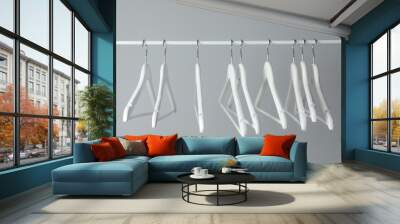 White clothes hangers on metal rail against light background Wall mural