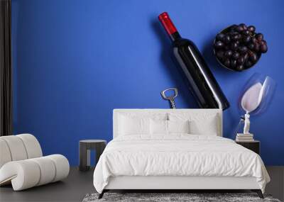 Wing corkscrew, wine, grapes and glass on blue background, flat lay. Space for text Wall mural