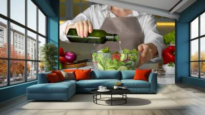 Woman adding cooking oil to delicious salad at table, closeup Wall mural