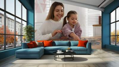 Woman and his little daughter playing with puzzles at home Wall mural