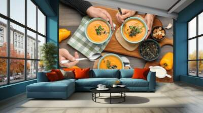 Woman and man eating delicious pumpkin soup at wooden table, top view Wall mural