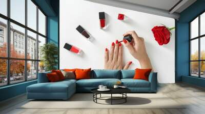 Woman applying bright nail polish on white background, top view Wall mural