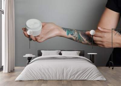 Woman applying cream on her arm with tattoos against light grey background, closeup Wall mural