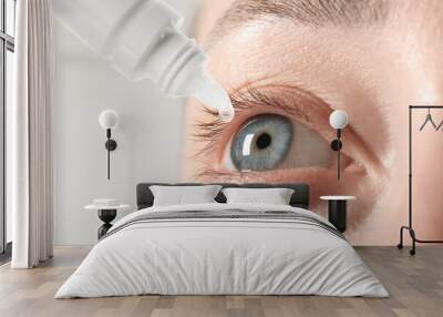 Woman applying eye drops on light background, closeup Wall mural