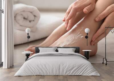 Woman applying moisturizing cream onto her feet on floor, closeup. Body care Wall mural