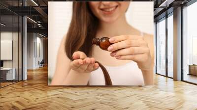 Woman applying oil hair mask indoors, closeup Wall mural