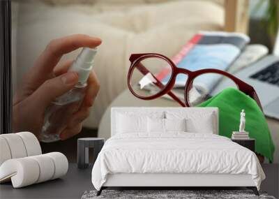 Woman cleaning glasses with microfiber cloth and spray at home, closeup Wall mural