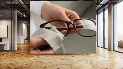 Woman cleaning glasses with microfiber cloth at home, closeup Wall mural