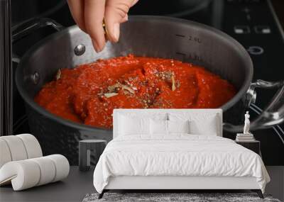 Woman cooking delicious tomato sauce in pan on stove, closeup Wall mural