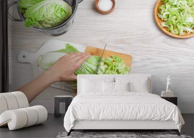 Woman cutting Chinese cabbage at white wooden kitchen table, top view Wall mural