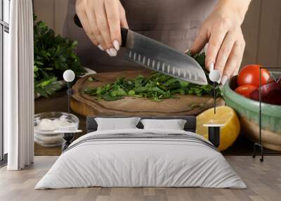 Woman cutting fresh parsley at wooden table, closeup Wall mural