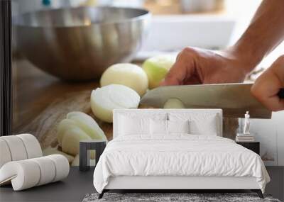 Woman cutting fresh ripe onion on wooden board indoors, closeup Wall mural