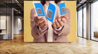 woman demonstrating sim cards of different sizes on yellow background, closeup Wall mural