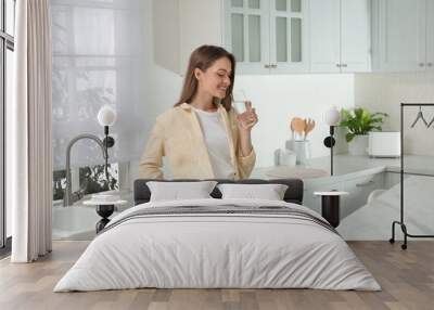 Woman drinking tap water from glass in kitchen Wall mural