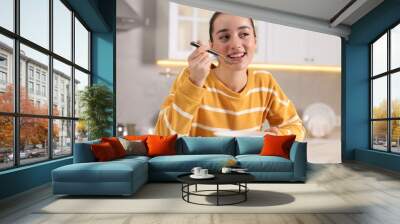 Woman eating tasty soup at white table in kitchen Wall mural