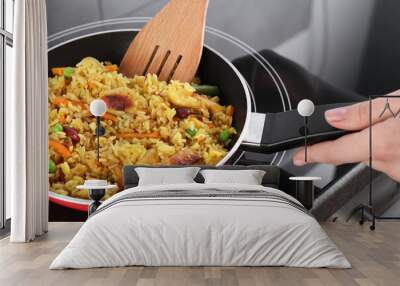 Woman frying rice with meat and vegetables on induction stove, closeup Wall mural