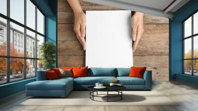 Woman holding blank paper sheets for brochure at wooden table, top view. Mock up Wall mural