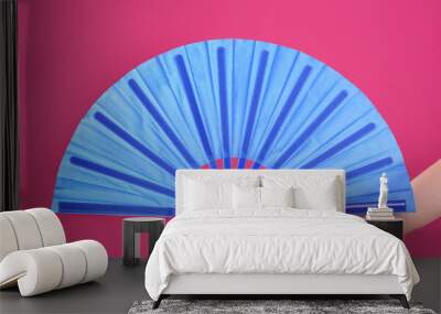 Woman holding blue hand fan on pink background, closeup Wall mural