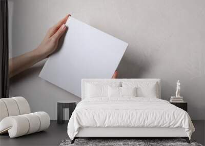 Woman holding book with blank cover at white table, top view. Mockup for design Wall mural