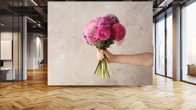 Woman holding bouquet of beautiful aster flowers on beige background, closeup Wall mural