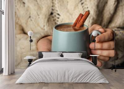 Woman holding cup of delicious hot cocoa with cinnamon, closeup Wall mural