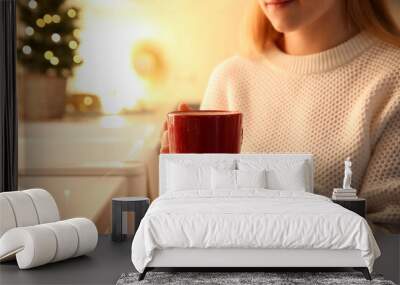 Woman holding cup with hot drink in kitchen, closeup Wall mural