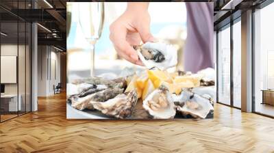 Woman holding fresh oyster over plate, focus on hand Wall mural