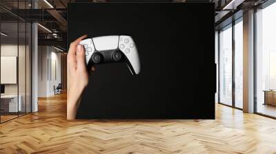 Woman holding game controller on black background, closeup. Space for text Wall mural