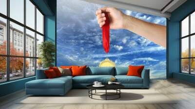 Woman holding gold medal in hand against sky, closeup Wall mural