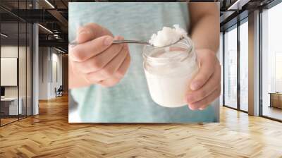 Woman holding jar and spoon with coconut oil, closeup. Healthy cooking Wall mural