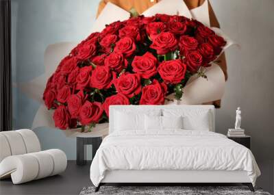 Woman holding luxury bouquet of fresh red roses on light background, closeup Wall mural