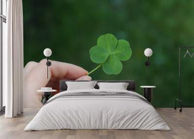 Woman holding one beautiful green clover leaf outdoors, closeup Wall mural