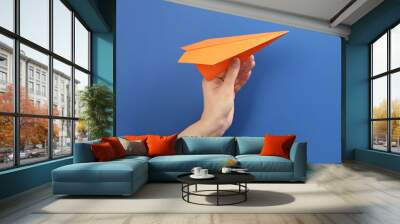 Woman holding paper plane on blue background, closeup Wall mural