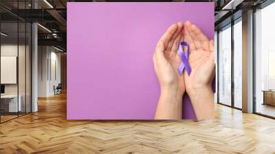 Woman holding purple ribbon on lilac background, top view with space for text. Domestic violence awareness Wall mural