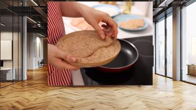 Woman holding raw schnitzels with breadcrumbs in kitchen, closeup Wall mural