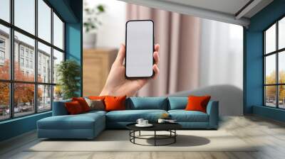 Woman holding smartphone in hand at home, closeup. Space for text Wall mural