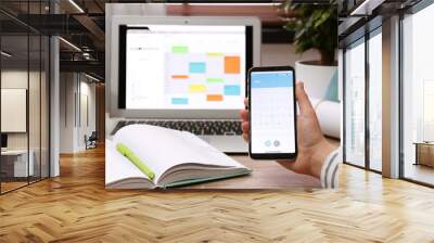 Woman holding smartphone with calendar app at table, closeup Wall mural