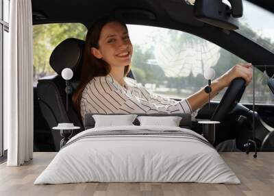 Woman holding steering wheel while driving car Wall mural