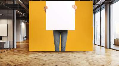 Woman holding white blank poster on yellow background. Mockup for design Wall mural