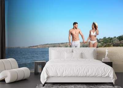 Woman in bikini and her boyfriend on beach, space for text. Happy couple Wall mural