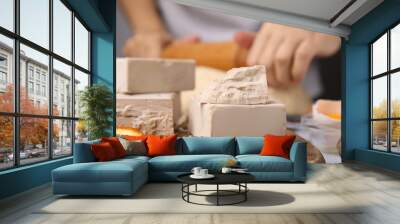 Woman kneading dough at table, focus on blocks of compressed yeast Wall mural