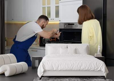 Woman looking how repairman fixing oven in kitchen Wall mural