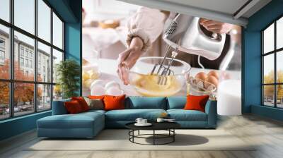 Woman making dough with mixer in bowl at table, closeup Wall mural