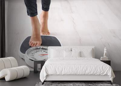 Woman measuring her weight using scales on floor Wall mural