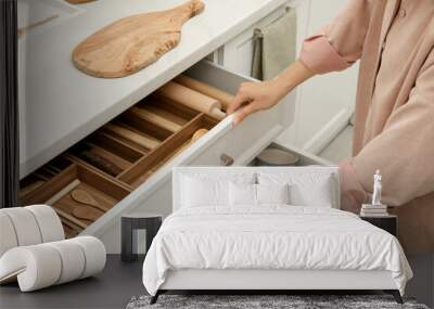 woman opening drawers of kitchen cabinet with different dishware and utensils, closeup Wall mural