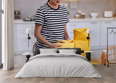 Woman packing lunch box with healthy food at wooden table in kitchen, closeup. Preparing for school Wall mural